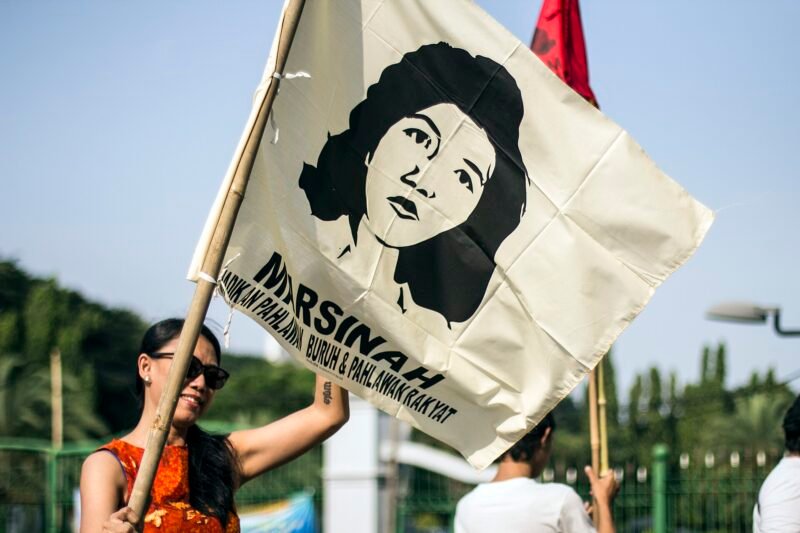 Ilustrasi gerakan buruh Indonesia, peserta aksi mengibarkan bendera bergambar Marsinah, ikon perjuangan buruh. (Foto: Wikimedia Commons, CC BY 2.0)